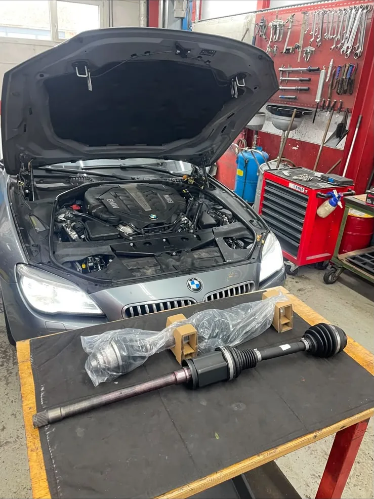 BMW 6er mit geöffneter Motorhaube, neue Antriebswellen bereit zum Einbau