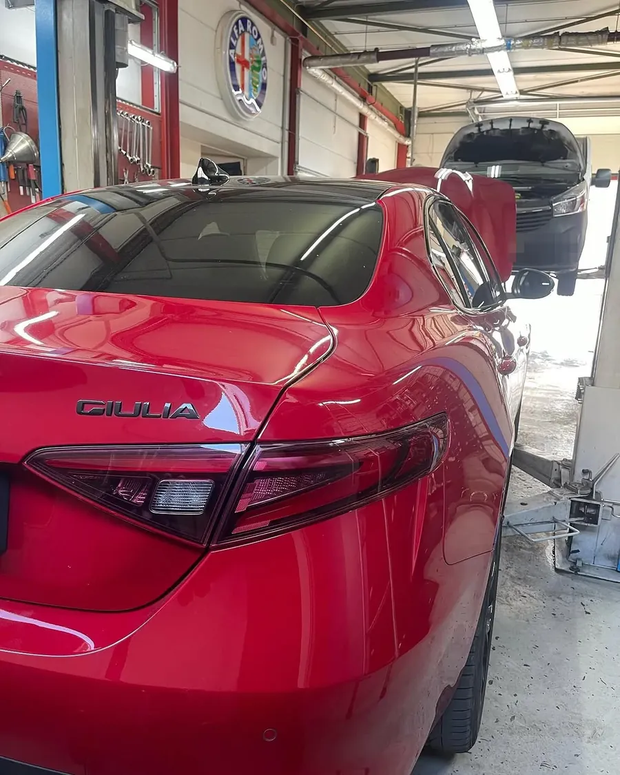 Heckansicht einer Alfa Romeo Giulia in der Werkstatt mit Alfa-Romeo-Leuchtreklame