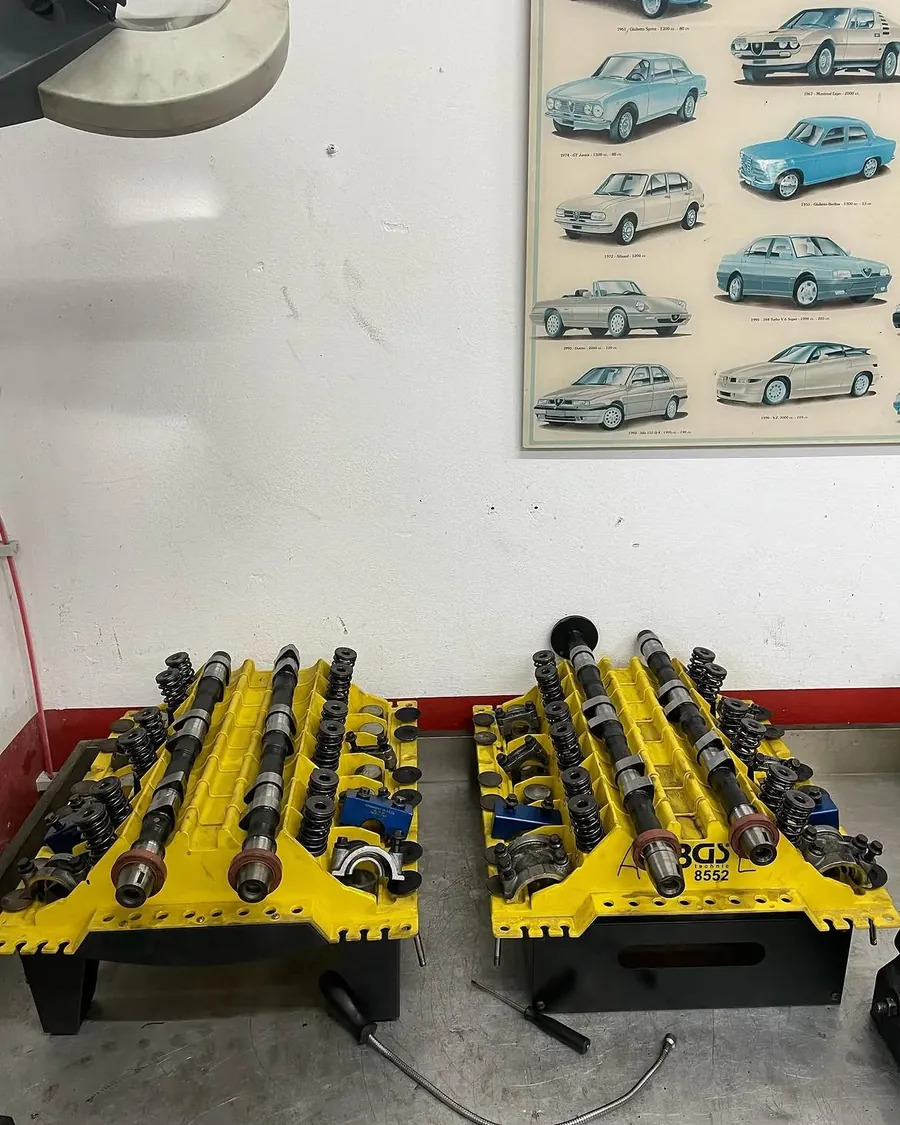 Nockenwellen und Ventiltrieb eines Alfa Romeo V6, sortiert auf Montageträgern
